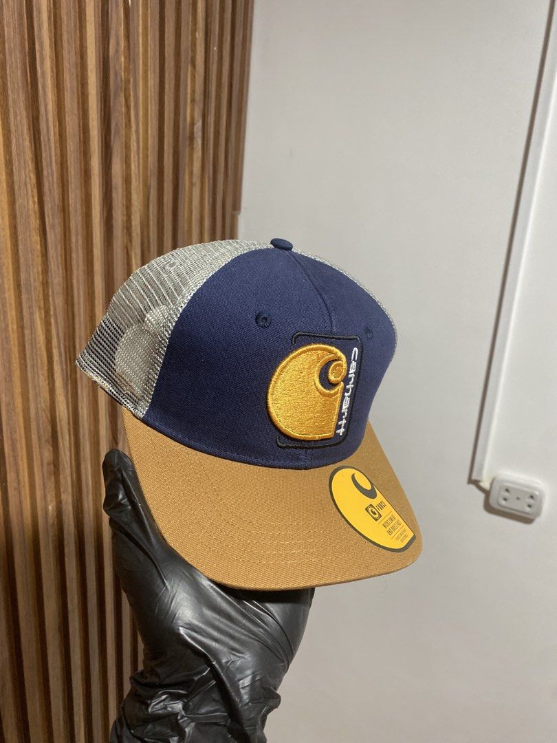 Carousell Carhartt Force Trucker Hat Navy Brown (Category: Caps & Hats) located in Caloocan City. Submitted by heatedcaps4425 (Listing ID 1467803741, Image 2). Description: - Brand: Carhartt Force - Style: Trucker hat / snapback - Color: Navy blue front, brown flat brim, grey mesh back - Details: Iconic embroidered logo patch on the front - Condition: Brand new with original tags and brim sticker attached - Closure: Adjustable snapback.