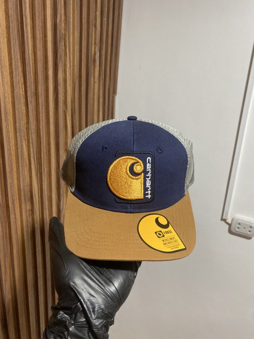 Carousell Carhartt Force Trucker Hat Navy Brown (Category: Caps & Hats) located in Caloocan City. Submitted by heatedcaps4425 (Listing ID 1467803741, Image 1). Description: - Brand: Carhartt Force - Style: Trucker hat / snapback - Color: Navy blue front, brown flat brim, grey mesh back - Details: Iconic embroidered logo patch on the front - Condition: Brand new with original tags and brim sticker attached - Closure: Adjustable snapback.