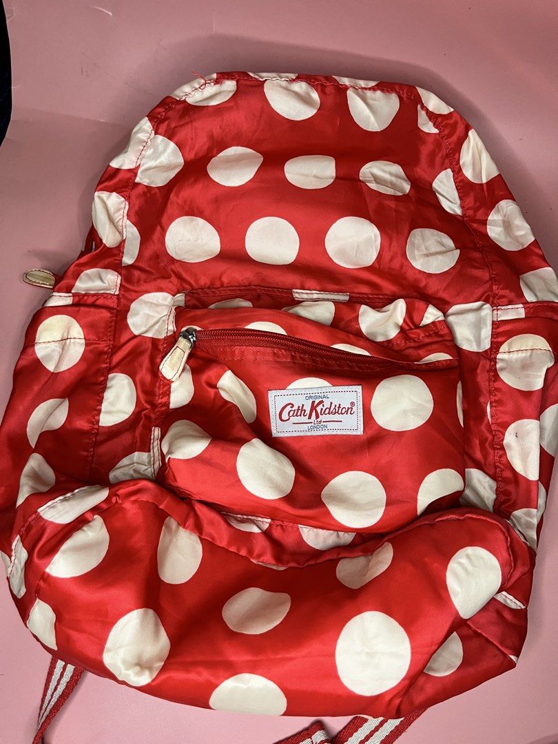 Cath Kidston Red Polka Dot Backpack (Category: Backpacks) located in Caloocan City. Submitted by snapshop_ph (Listing ID 1467644915, Image 1). Description: - Brand/Model: Authentic Cath Kidston Backpack - Design: Classic red and white polka dot pattern with matching interior lining - Features: Front zip pocket, fabric straps, and interior slip pocket - Condition: Clean interior; minor yellowing on exterior fabric spots near zippers and upper edge