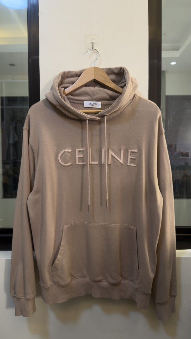 Celine Beige Logo Hoodie Pullover (Category: Hoodies) located in Paranaque City. Submitted by mykapoynton (Listing ID 1467806135, Image 2). Description: Celine Beige Logo Hoodie Pullover - Design: Bold CELINE chest lettering with clean Paris neck label - Features: Drawstring hood and front kangaroo pocket - Fit: Standard fit with ribbed cuffs and hem to hold shape - Material: Soft and comfortable cotton blend - Style: Minimalist streetwear, easy 