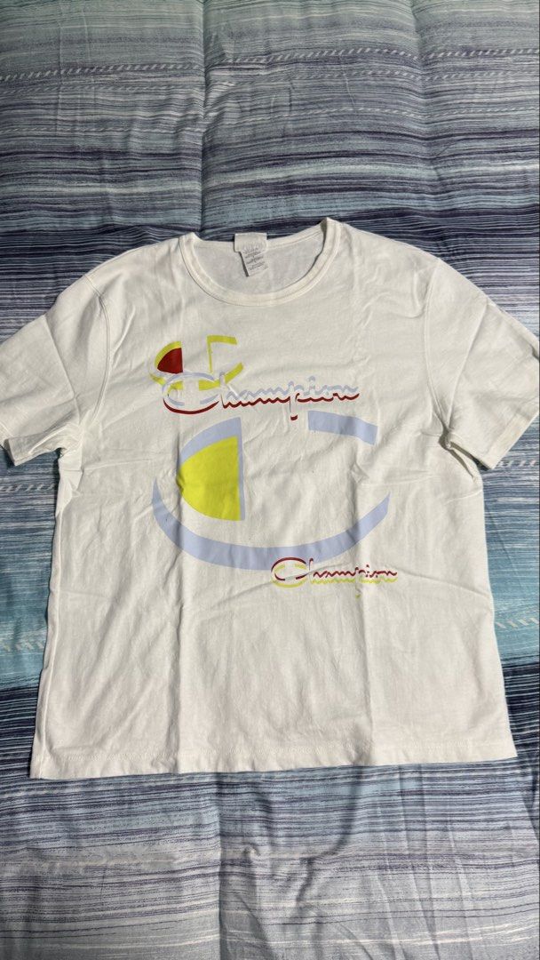 Champion White Graphic Print Tee Size L (Category: Tshirts & Polo Shirts ) located in Quezon City. Submitted by kobeeeee_12 (Listing ID 1467641219, Image 1). Description: - Brand: Champion - Color: White with large colorful front logo - Size: L (Length: approx. 25 inches) - Condition: Excellent, clean with no stains or holes - Style: Classic crew neck, short sleeves, great for daily casual wear.