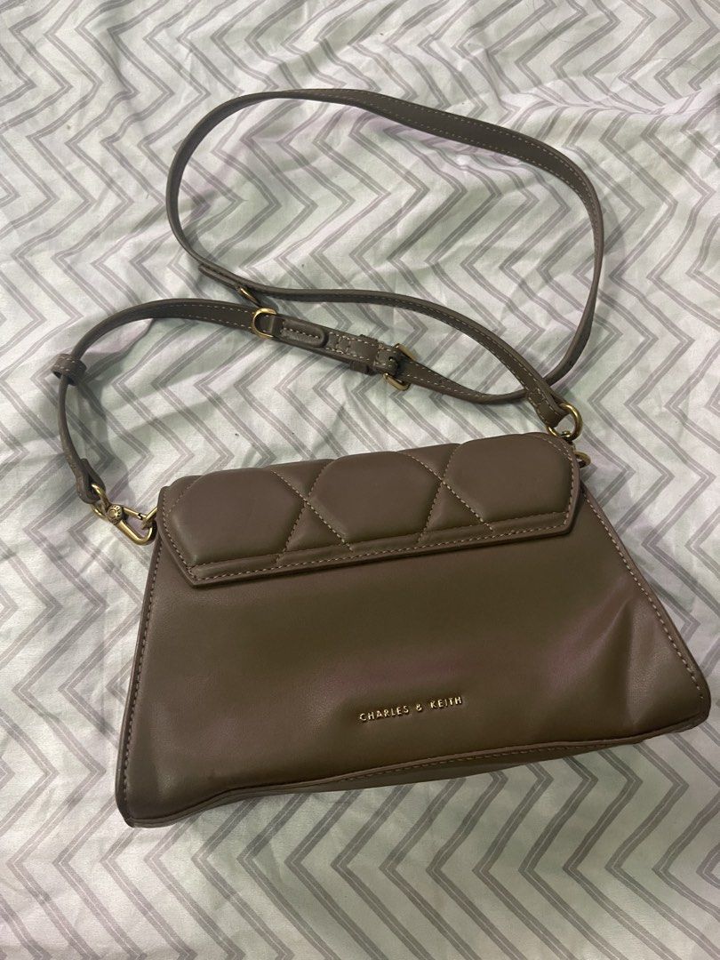 Charles & Keith Quilted Crossbody Bag (Category: Cross-body Bags) located in Navotas City. Submitted by itsjhen12 (Listing ID 1467705906, Image 2). Description: - Brand: Charles & Keith - Color: Elegant taupe brown - Material: Smooth, structured faux leather - Design: Quilted flap with a unique front twist lock closure - Hardware: Gold-tone metal accents and subtle gold branding on the back - Strap: Adjustable shoulder strap for a custom fit - Ca