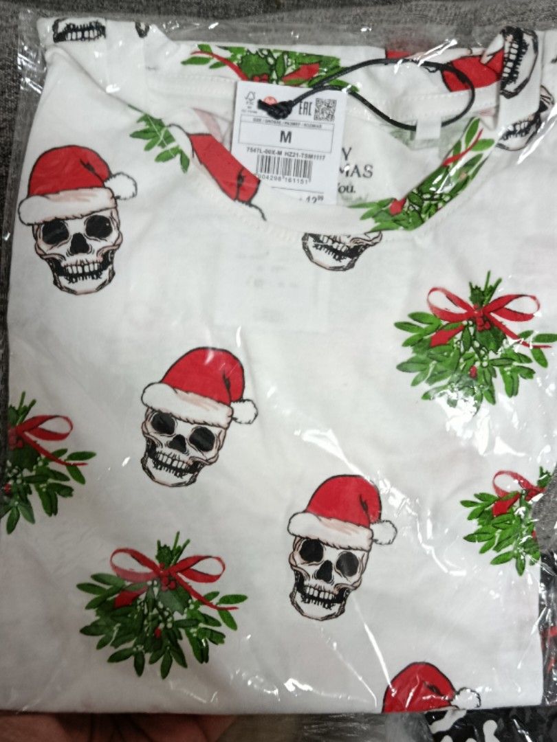 Christmas Graphic T-Shirts (Category: Tshirts & Polo Shirts ) located in Quezon City. Submitted by robelles_thriftshop (Listing ID 1467774970, Image 1). Description: - Quantity: Set of 2 Christmas graphic t-shirts - Size: Medium (M) - Designs: 1 white (skull and mistletoe print) and 1 black (various holiday skulls, bones, and text designs) - Condition: Brand new, never opened or worn, sealed in original plastic packaging with retail tags attached