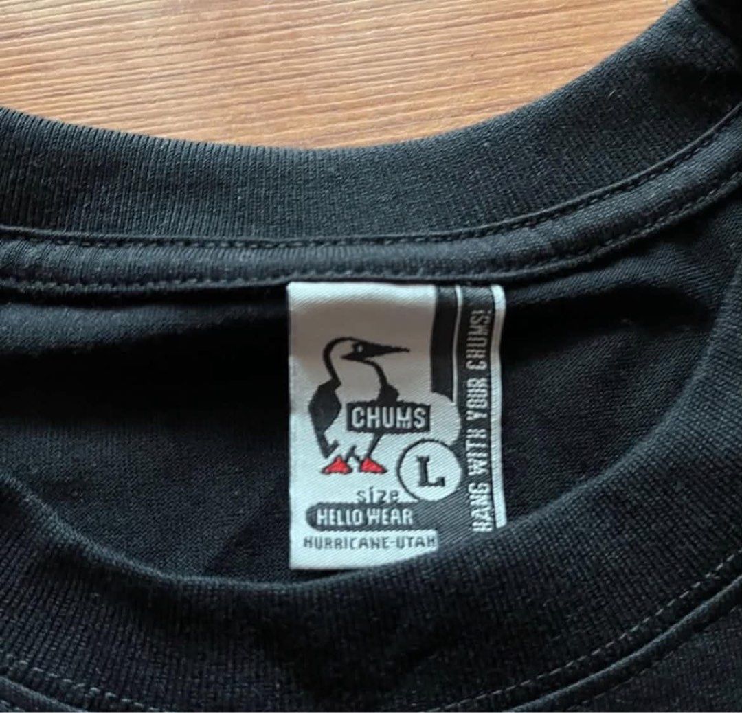 Chums Black T-Shirt (Category: Tshirts & Polo Shirts ) located in Rizal. Submitted by timelessfinds89_ (Listing ID 1467673247, Image 2). Description: - Brand: Chums - Color: Black - Size: Large (tag inside collar) - Design: Front graphic of the booby bird working out with dumbbells and kettlebells, with 'TRAIN LIKE A BOOBY BIRD' text - Details: Chums woven patch at the bottom hem - Condition: Clean fabric, bright print colors, no stains or holes 