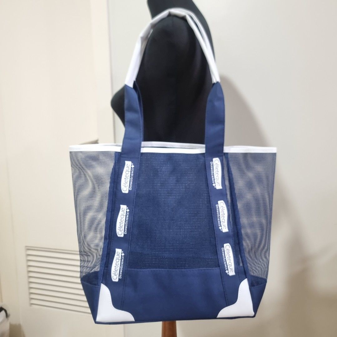 Céleteque Blue Mesh Tote Bag (Category: Tote Bags) located in Pasig City. Submitted by lesmitch (Listing ID 1467645802, Image 1). Description: - Color: Navy blue and white - Material: Lightweight mesh body with solid blue trim - Design: Open top with sturdy handles, white bottom corner reinforcements, and printed strap branding ~ Check all photos for the item's actual condition and measurements ~ Payment is via gcash, pay maya or bdo ~ Shipping i