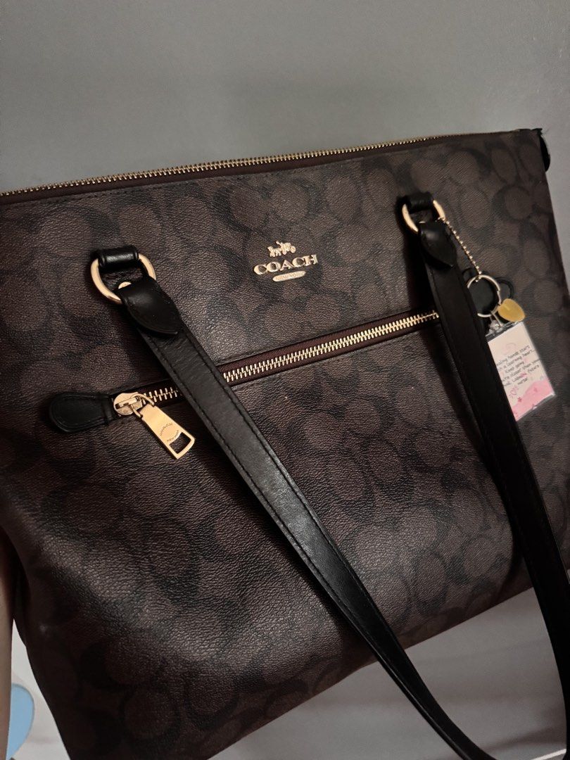 Coach Brown Signature Monogram Tote Bag (Category: Luxury Bags & Wallets) located in Cebu City. Submitted by ixiaces (Listing ID 1467652138, Image 2). Description: - Authentic Brown Coach Tote Bag with Signature Monogram Print - Stylish black leather shoulder straps with gold-tone hardware - Top zipper closure and handy front zip pocket with matching pull - Includes a cute bonus nurse keychain attached to the strap rings - Condition: Minor wear s