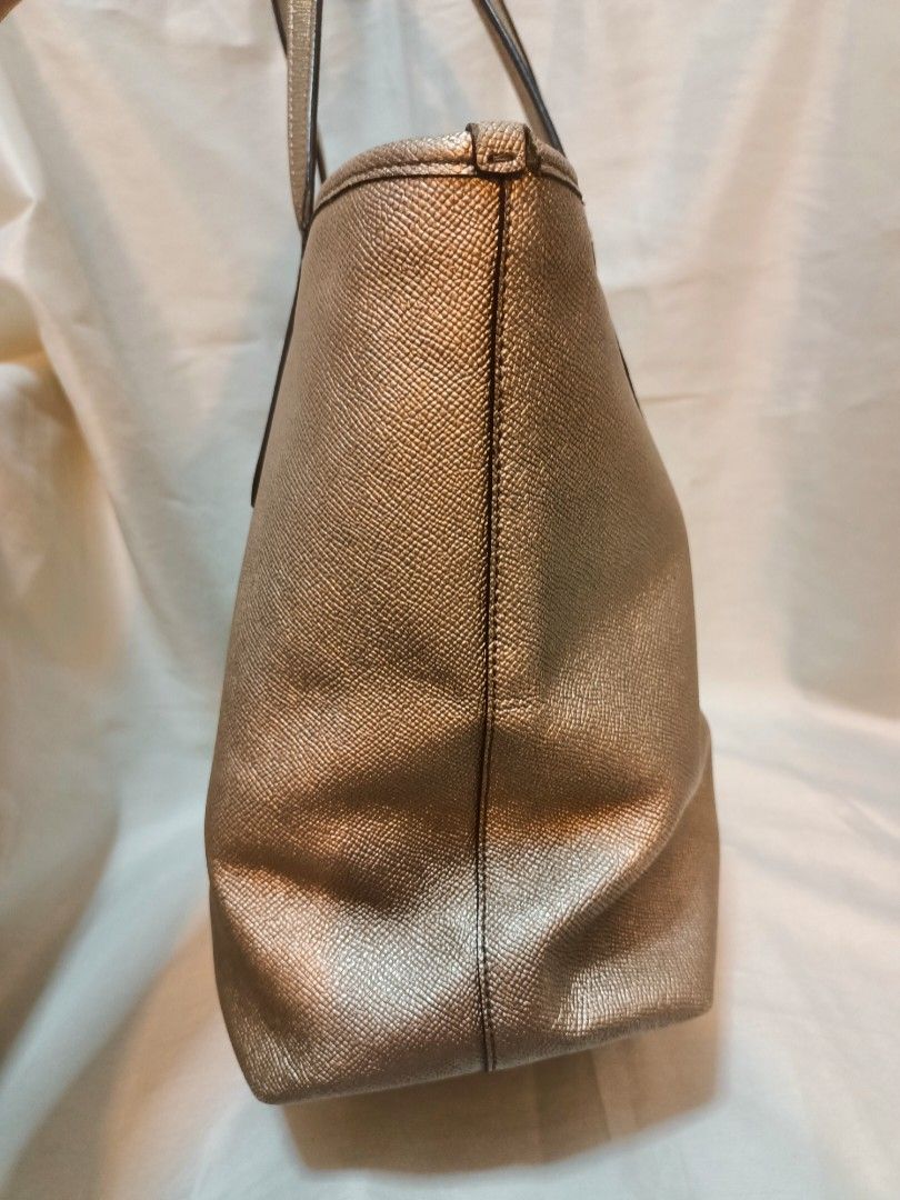 Coach Metallic Gold Leather Tote Bag (Category: Luxury Bags & Wallets) located in Manila. Submitted by preloved439 (Listing ID 1466651433, Image 3). Description: - Coach tote bag in a stunning metallic gold textured leather - Medium size - Dual shoulder straps accented with chic gold-tone hardware studs - Classic Coach New York logo on the front - Spacious main interior compartment for all your daily essentials - Clean stitching and durable const