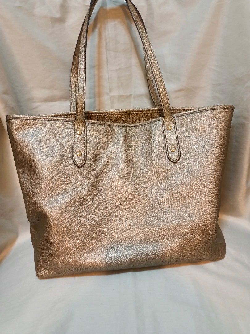 Coach Metallic Gold Leather Tote Bag (Category: Luxury Bags & Wallets) located in Manila. Submitted by preloved439 (Listing ID 1466651433, Image 2). Description: - Coach tote bag in a stunning metallic gold textured leather - Medium size - Dual shoulder straps accented with chic gold-tone hardware studs - Classic Coach New York logo on the front - Spacious main interior compartment for all your daily essentials - Clean stitching and durable const