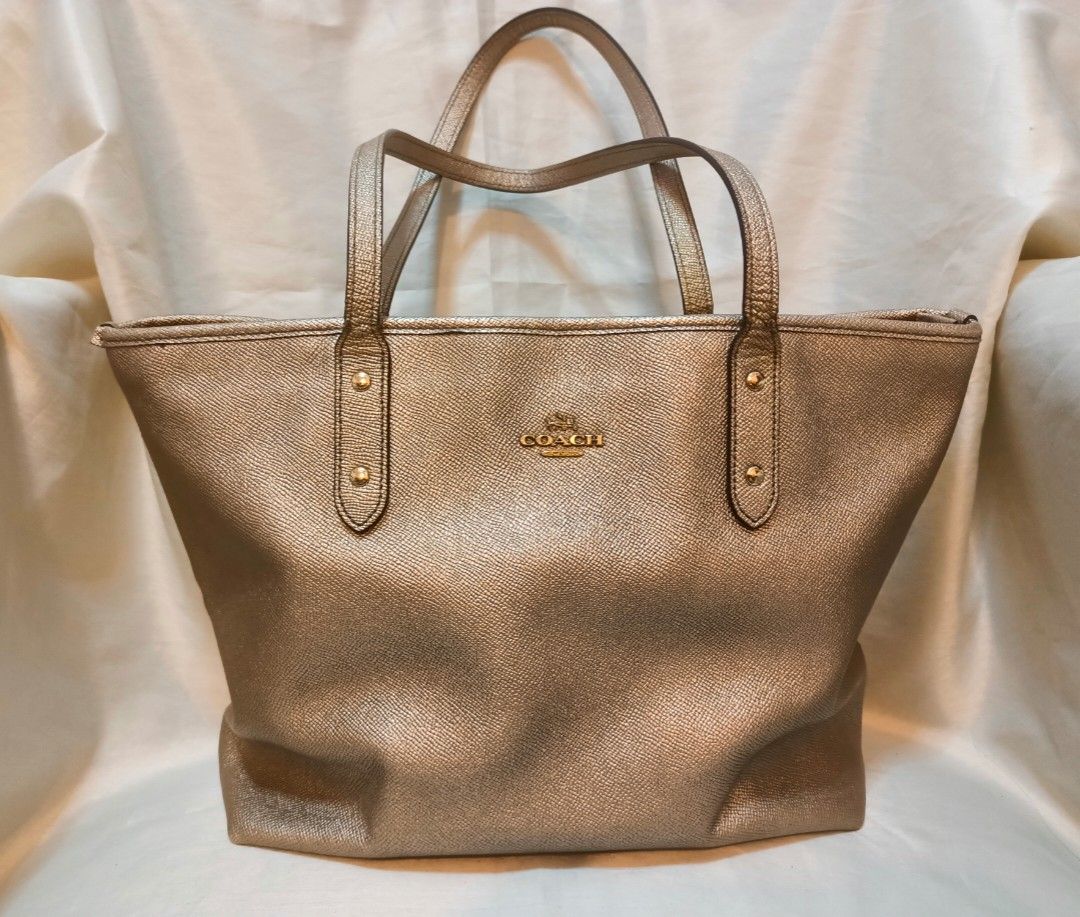 Coach Metallic Gold Leather Tote Bag (Category: Luxury Bags & Wallets) located in Manila. Submitted by preloved439 (Listing ID 1466651433, Image 1). Description: - Coach tote bag in a stunning metallic gold textured leather - Medium size - Dual shoulder straps accented with chic gold-tone hardware studs - Classic Coach New York logo on the front - Spacious main interior compartment for all your daily essentials - Clean stitching and durable const