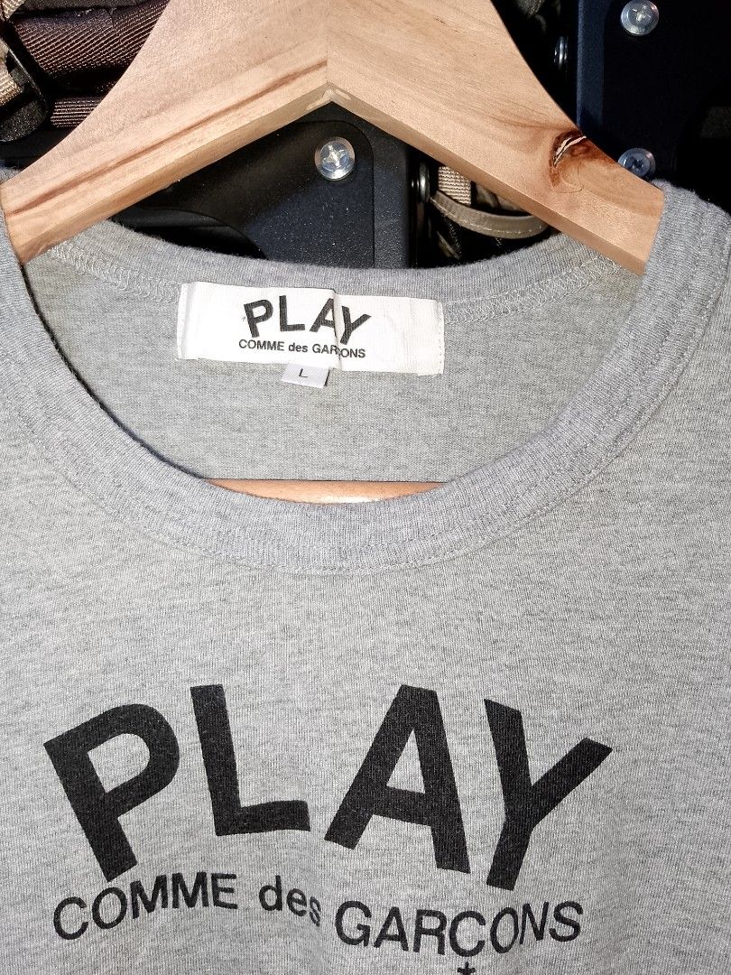 COMME des GARCONS PLAY grey t-shirt large (Category: Shirts) located in Manila. Submitted by mjthrifted_second (Listing ID 1467647180, Image 3). Description: - Brand: PLAY Comme des Garçons - Color: Grey - Size: Tagged L -Dimes: 18/24 - Design: Big black heart graphic on back with PLAY COMME des GARÇONS text logo on the chest - Material: 100% cotton - Origin: Made in Japan - Condition: Clean neck tag and wash label included.