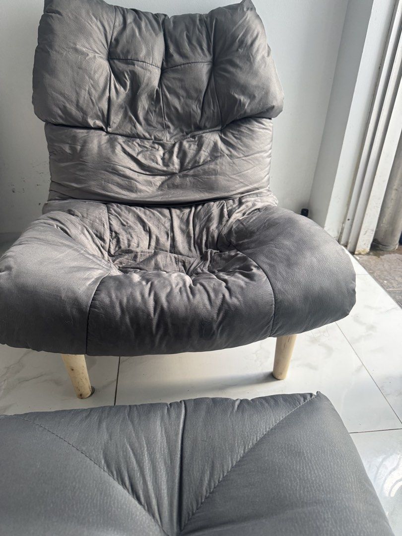 Dark grey lounge armchair with matching footstool (Category: Chairs) located in Manila. Submitted by decluterthings888 (Listing ID 1467693313, Image 1). Description: - Puffy lounge chair with matching footstool in dark grey (faux leather or fabric) - Deep cushioning on backrest and seat for ultimate comfort - Supported by sturdy light wood legs - Ideal for the living room or bedroom, great for reading and movie nights - Note: Features some natura
