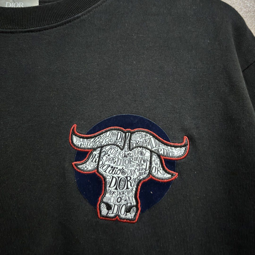 Dior Buffalo Embroidered Black T-shirt (Category: Tshirts & Polo Shirts ) located in Batangas. Submitted by phthriftpingzz (Listing ID 1467696421, Image 2). Description: - Brand: Dior - Color: Black - Size: L - Material: 100% Cotton, Made in Italy - Design: Buffalo chest patch with text pattern & blue embroidered Dior branding on the right sleeve - Fit: Crew neck, short sleeves - Condition: Clean fabric and solid construction.