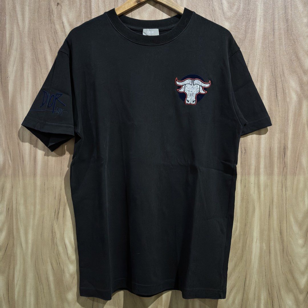 Dior Buffalo Embroidered Black T-shirt (Category: Tshirts & Polo Shirts ) located in Batangas. Submitted by phthriftpingzz (Listing ID 1467696421, Image 1). Description: - Brand: Dior - Color: Black - Size: L - Material: 100% Cotton, Made in Italy - Design: Buffalo chest patch with text pattern & blue embroidered Dior branding on the right sleeve - Fit: Crew neck, short sleeves - Condition: Clean fabric and solid construction.