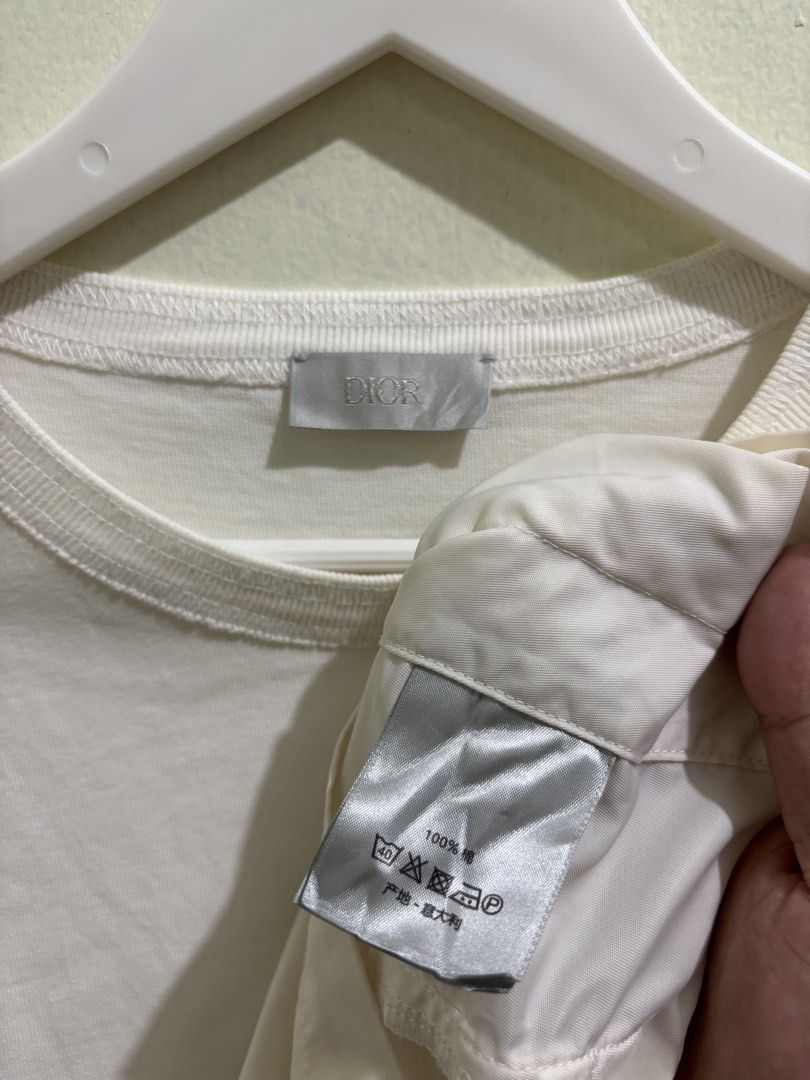 Dior x Sacai (Category: Tshirts & Polo Shirts ) located in Daraga. Submitted by hannieldustin (Listing ID 1467634884, Image 3). Description: - Brand: Dior - Color: White - Size: Medium (M) - Material: 100% Cotton, Made in Italy - Features: Chest pocket with zip compartment, embroidered Dior branding, and unique layered fabric paneling down both sides - DM for measurements or fast shipping!.