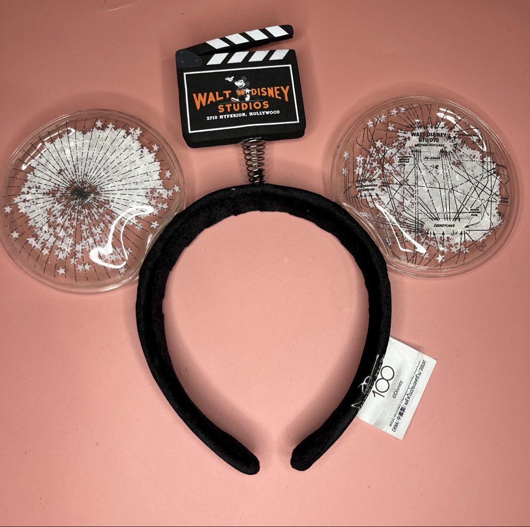 Disney 100 Walt Disney Studios Mickey Mouse Ears Headband (Category: Hair Accessories) located in Caloocan City. Submitted by snapshop_ph (Listing ID 1467645331, Image 1). Description: - Authentic Disney 100 Years of Wonder collection - Comfortable black velvet headband with official silver Disney 100 tag - Clear plastic bubble ears filled with a Walt Disney Studios Hollywood theme and white starbursts - Features an adorable miniature black movie