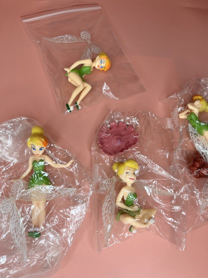 Disney Tinker Bell Figurines Set with Accessories (Category: Figurines & Statues) located in Caloocan City. Submitted by snapshop_ph (Listing ID 1467644612, Image 2). Description: - Set of 4 Tinker Bell figures in individual plastic bags - Features assorted poses: sitting, standing, and reclining - Includes a pink flower accessory and a brown base piece - Detailed green dresses and translucent wings - Great addition to any Disney collection or as