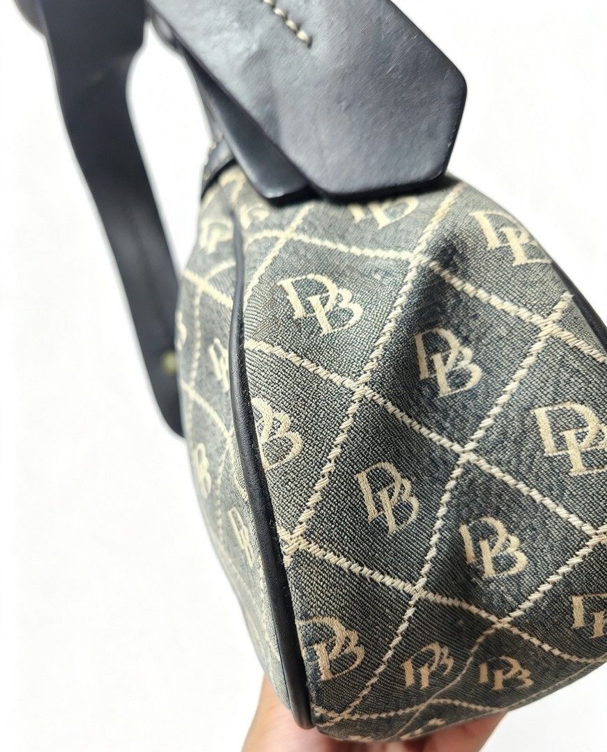 Dooney & Bourke Monogram Shoulder Bag with Front Zippers (Category: Luxury Bags & Wallets) located in Manila. Submitted by jialyn03310_tree (Listing ID 1467832972, Image 3). Description: Grey canvas shoulder bag featuring an all-over monogram pattern, black leather trim, and contrast white stitching. Includes two front zipper pockets, silver-tone hardware, and a secure top zip closure. Clean interior..