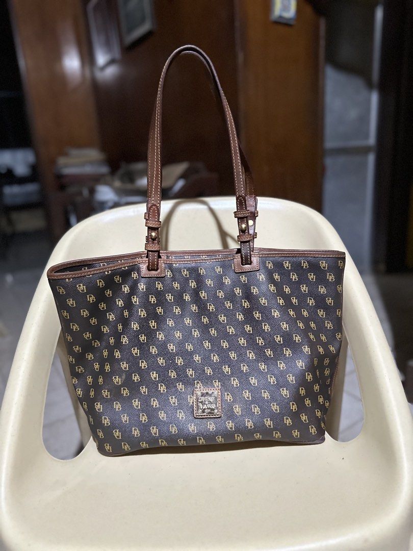 Dooney & Bourke Monogram Tote Bag Brown (Category: Luxury Bags & Wallets) located in Manila. Submitted by orcharchives (Listing ID 1467736811, Image 1). Description: ‼️MINORS FLAWS SA CORNER MAY RUBBINGS BARELY NOTICEABLE SEE LAST PIC ‼️ -Classic brown tote bag featuring a stylish DB monogram print - Double shoulder straps with buckle adjustments for a custom fit - Secure zip-top closure to keep your essentials safe - Striking vibrant red interio