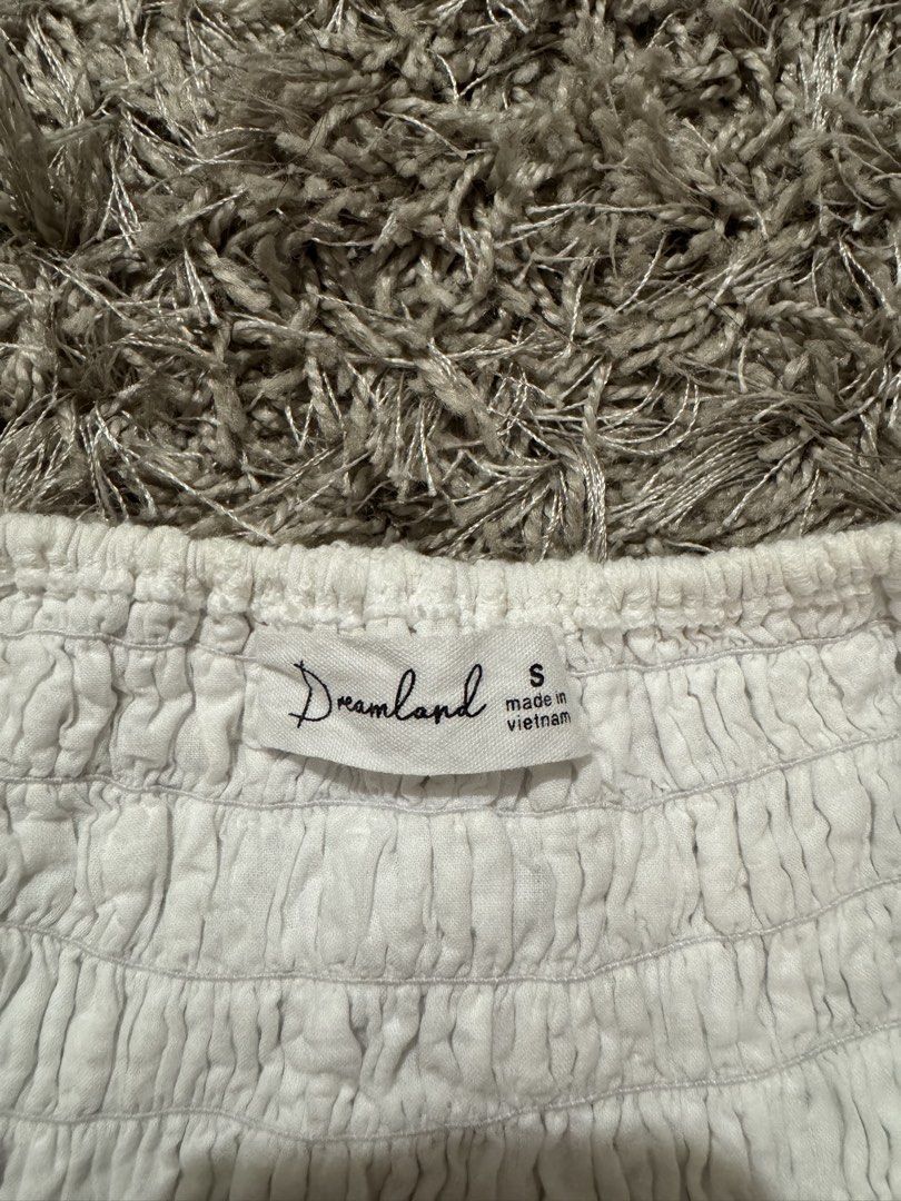 Dreamland White Eyelet Ruffle Crop Top Size S (Category: Blouses) located in Caloocan City. Submitted by newcrystal_3b43ba (Listing ID 1467738539, Image 3). Description: - Brand: Dreamland - Size: Small (tag attached) - Color: Clean white with intricate floral eyelet cutouts - Design: Square neckline with ruffle shoulder straps - Closure: Button-front with a stretchy smocked back panel - Detail: Layered ruffle hem.
