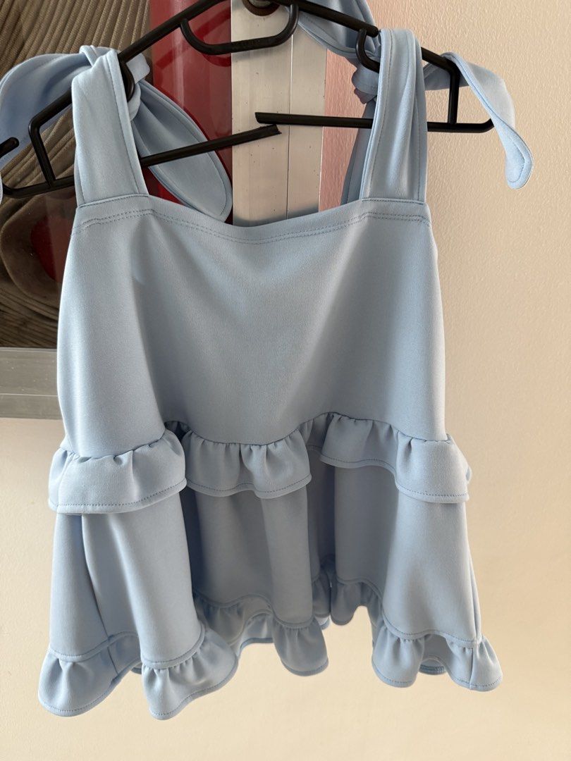 Everyday Casuals Light Blue Ruffle Tiered Cami Top (Category: Sleeveless) located in Mandaluyong City. Submitted by declutteringmylife101 (Listing ID 1467634553, Image 1). Description: - Brand/Style: Light blue cami top from Everyday Casuals - Design: Layered ruffles on front and back with adjustable self-tie ribbon straps - Cut: Straight neckline and sleeveless - Fabric: Soft, lightweight, and flowy material ideal for warm weather.