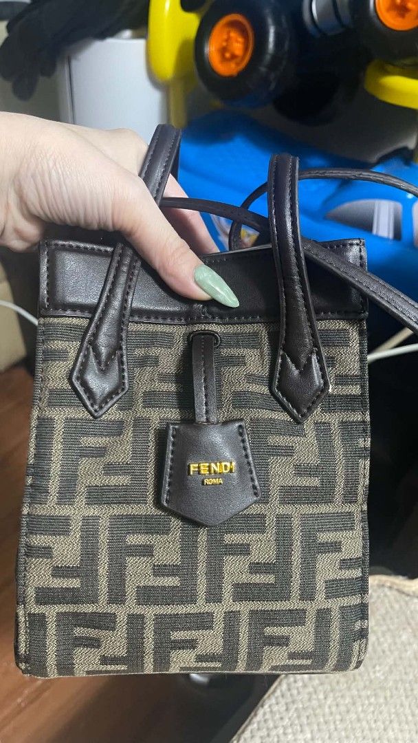 Fendi Mini Tote Bag (Category: Shoulder Bags) located in Manila. Submitted by jjm-collections (Listing ID 1467641893, Image 2). Description: - Fendi mini tote bag - Classic brown Zucca monogram canvas with matching leather handles and trim - Elegant gold-tone dangling Fendi Roma logo charm on the front - Clean black fabric interior lining with official Fendi Made in Italy leather tag - Compact and lightweight size, ideal for everyday essentials -