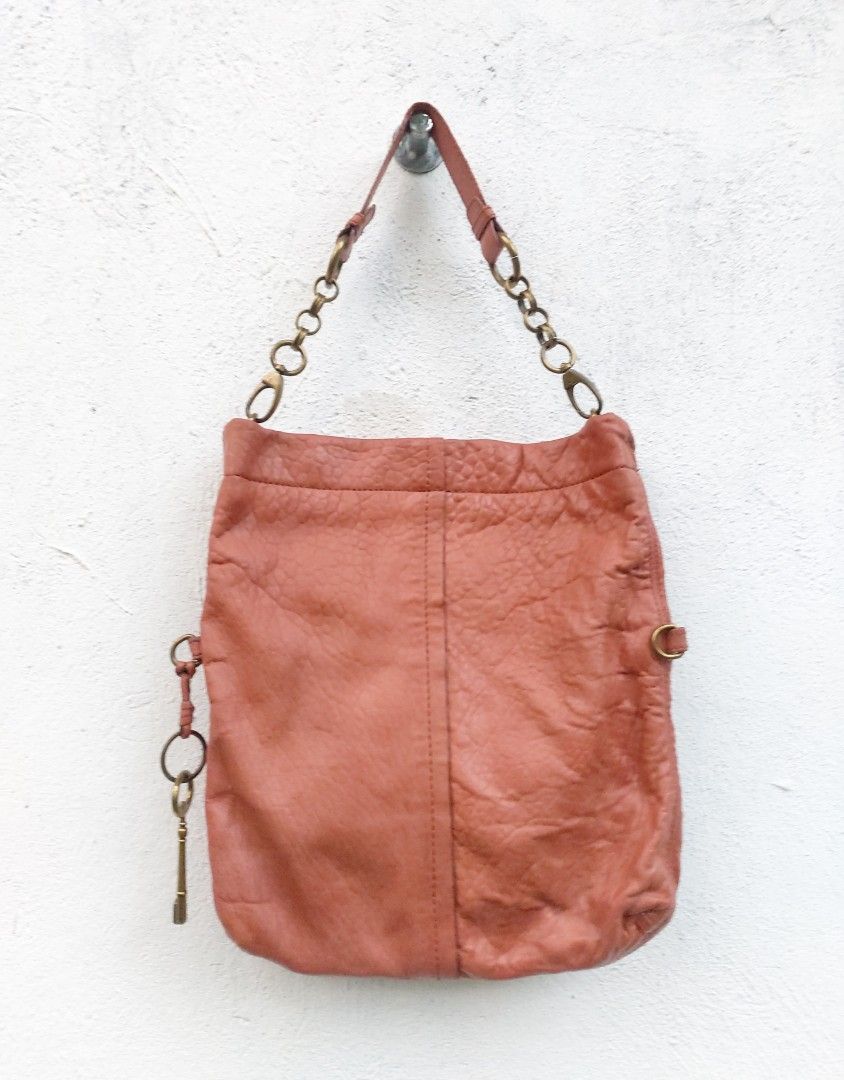 Fossil Leather Shoulder Bag with Key Charm (Category: Shoulder Bags) located in Lapu Lapu. Submitted by agnesapm_29813 (Listing ID 1467733235, Image 2). Description: - Authentic Fossil leather shoulder bag in rustic coral pink - Versatile fold-over design (wear extended or folded down) - Brass-tone chain strap hardware and matching key charm - Iconic Fossil keyhole logo plate on the front - Crafted from soft, textured leather with natural crinkle