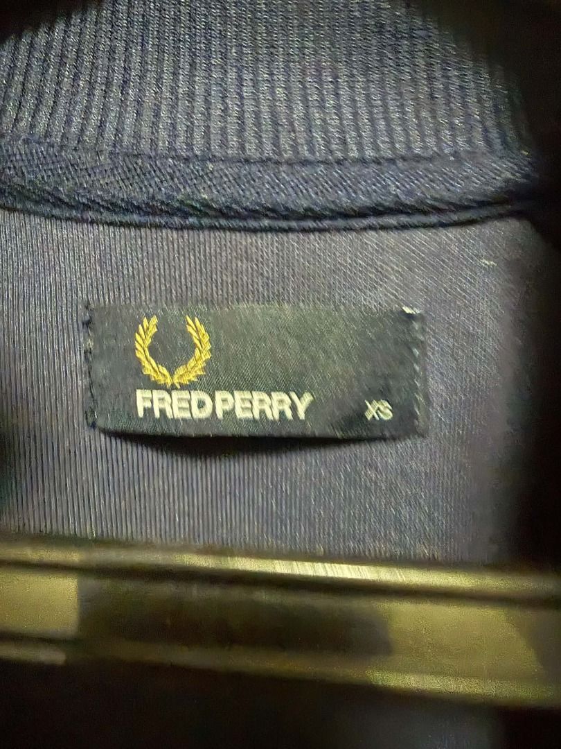 Fred Perry Navy Jacket Size XS (Category: Coats, Jackets and Outerwear) located in Quezon City. Submitted by chadermeister (Listing ID 1467730656, Image 3). Description: - Brand: Fred Perry - Color: Navy -Chequerboard print - Size: XS (tag stitched inside collar) - Material/Texture: Ribbed fabric with classic knit collar - Detail: Embroidered laurel wreath logo - Condition: Clean overall, great casual staple.