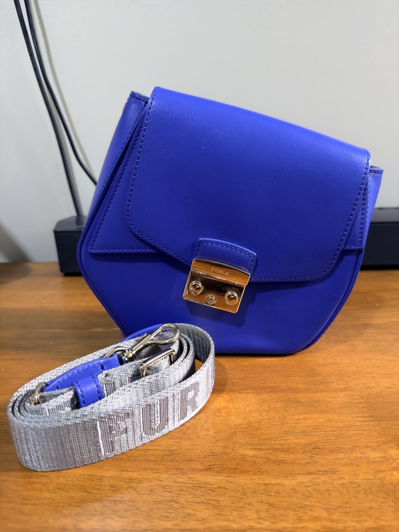 Furla Metropolis Prisma Mini in Blue (Category: Cross-body Bags) located in Quezon City. Submitted by milkybutter21 (Listing ID 1467662262, Image 1). Description: - Brand: Furla - Material: Genuine blue leather with clean surface - Hardware: Polished gold-tone with engraved logo branding - Closure: Secure front flap closure - Strap: Adjustable grey woven strap with bold FURLA lettering and blue leather accents - Style: Structured shape, chic and 