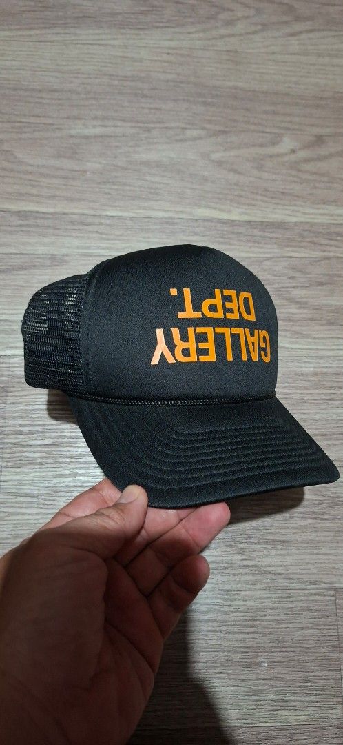 Gallery Dept. Upside down logo.trucker hat (Category: Caps & Hats) located in Makati City. Submitted by ruschenmor25535 (Listing ID 1467734110, Image 2). Description: - Brand: Gallery Dept. - Color: Black with bold orange front text - Condition: Brand new with tags attached - Features: Breathable mesh backing, adjustable plastic snapback - Origin: Made in USA with interior branding - Perfect for daily streetwear and casual fits.