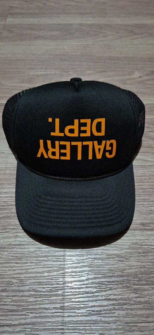 Gallery Dept. Upside down logo.trucker hat (Category: Caps & Hats) located in Makati City. Submitted by ruschenmor25535 (Listing ID 1467734110, Image 1). Description: - Brand: Gallery Dept. - Color: Black with bold orange front text - Condition: Brand new with tags attached - Features: Breathable mesh backing, adjustable plastic snapback - Origin: Made in USA with interior branding - Perfect for daily streetwear and casual fits.