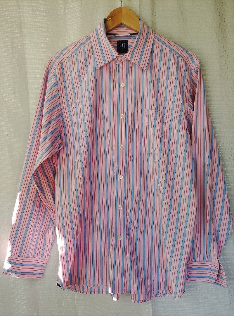 Gap Striped Classic Fit Button Down Shirt Size M (Category: Tshirts & Polo Shirts ) located in Tayum. Submitted by purephoenix.0f7166 (Listing ID 1467611820, Image 1). Description: - Brand: Gap - 22" x 31" dimensions - no issue excellent condition - Style: Classic fit long sleeve shirt - Pattern: Pink base with blue and red vertical stripes - Features: Collared neckline, button-front closure, single chest pocket - Size: Medium (Neck 15-15.5) - Or