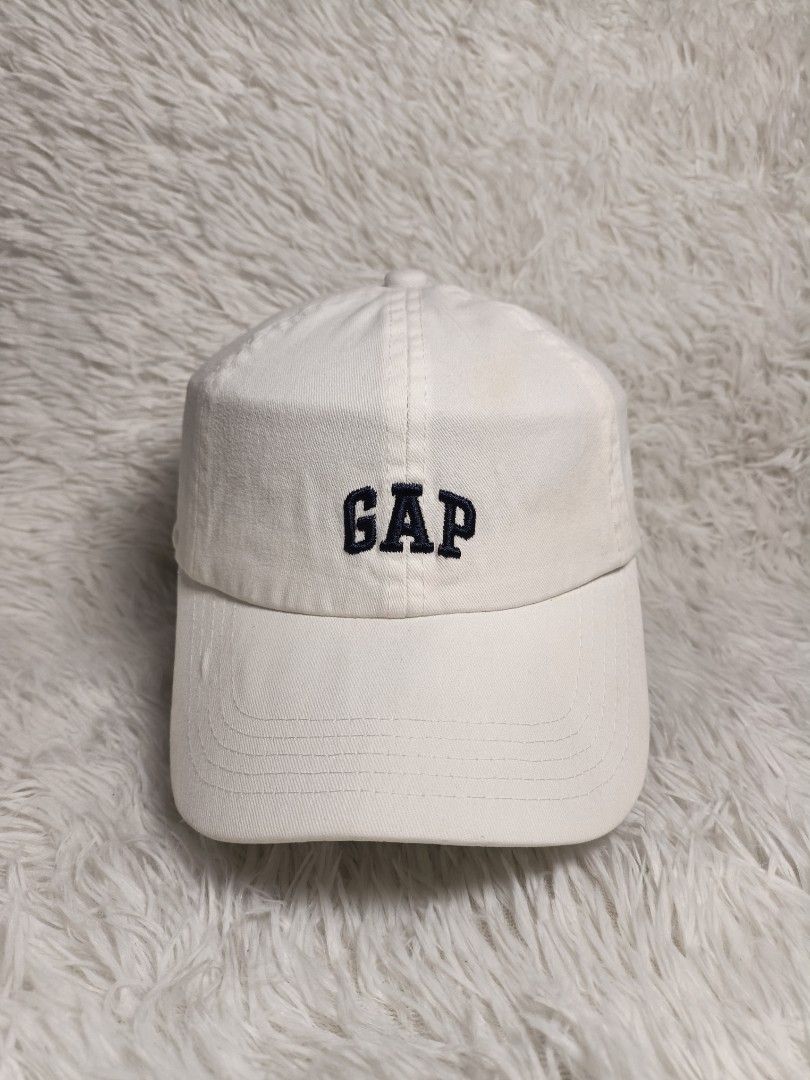 GAP White Baseball Cap (Category: Caps & Hats) located in Imus. Submitted by grindhouse.thriftshop (Listing ID 1467737638, Image 1). Description: - Brand: GAP - Color: White with navy blue embroidered logo - Material: 100% Cotton - Design: Classic six-panel with curved brim - Closure: Adjustable strapback with metal buckle.