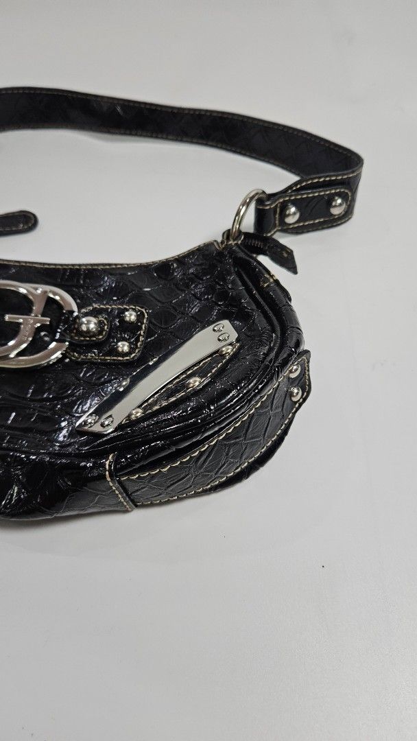 Guess Black Croc-Embossed Shoulder Bag (Category: Shoulder Bags) located in Alfonso. Submitted by jbcamet (Listing ID 1467709182, Image 3). Description: - Brand: Guess - Style: Shoulder bag - Material: Faux crocodile texture with polished finish - Hardware: Chunky silver-tone with large front G logo ring and metal corner accents - Closure: Top zipper - Interior: Classic monogram fabric lining, zip pocket, and Guess brand plaque - Strap: Short sho