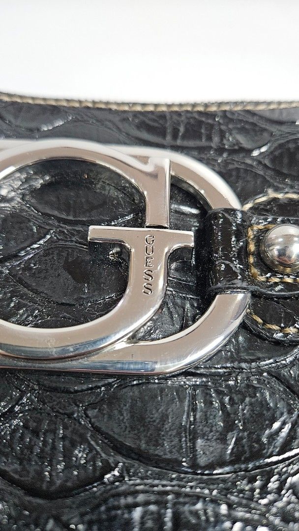 Guess Black Croc-Embossed Shoulder Bag (Category: Shoulder Bags) located in Alfonso. Submitted by jbcamet (Listing ID 1467709182, Image 2). Description: - Brand: Guess - Style: Shoulder bag - Material: Faux crocodile texture with polished finish - Hardware: Chunky silver-tone with large front G logo ring and metal corner accents - Closure: Top zipper - Interior: Classic monogram fabric lining, zip pocket, and Guess brand plaque - Strap: Short sho