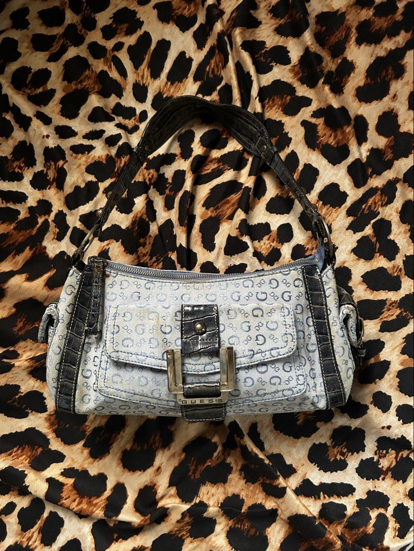 Guess Denim Monogram Shoulder Bag (Authentic) (Category: Shoulder Bags) located in Los Banos. Submitted by samsukehiro (Listing ID 1467716969, Image 1). Description: Guess shoulder bag in light blue denim with allover monogram print. Dark faux-croc leather trim and strap. Silver-tone hardware with buckle closure on front pocket. Zippered top and exterior zip pocket on back. Stud details along the shoulder strap. Y2K aesthetic. EXTERIOR NEEDS CLEA