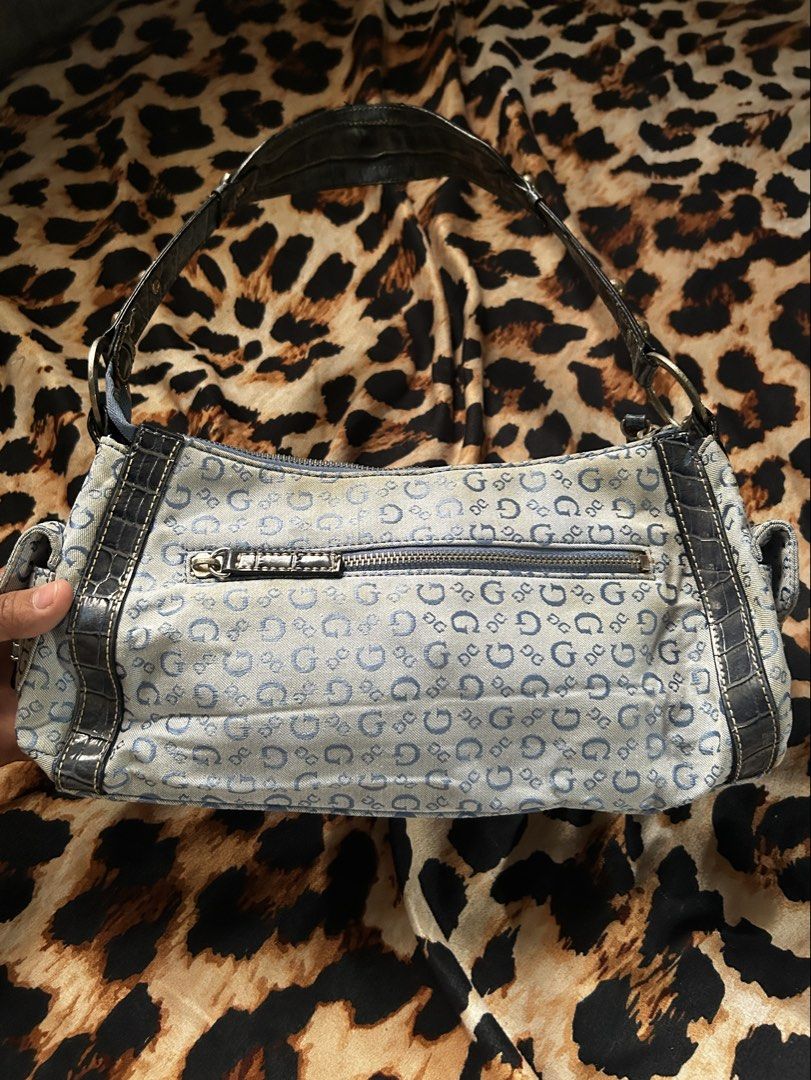 Guess Denim Monogram Shoulder Bag (Authentic) (Category: Shoulder Bags) located in Los Banos. Submitted by samsukehiro (Listing ID 1467716969, Image 2). Description: Guess shoulder bag in light blue denim with allover monogram print. Dark faux-croc leather trim and strap. Silver-tone hardware with buckle closure on front pocket. Zippered top and exterior zip pocket on back. Stud details along the shoulder strap. Y2K aesthetic. EXTERIOR NEEDS CLEA