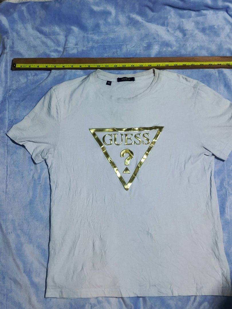 GUESS Gold Triangle Logo White T-Shirt (Category: Shirts) located in City of Isabela. Submitted by warmbird.d06e6f (Listing ID 1467637529, Image 2). Description: - Authentic Guess t-shirt in classic white - Features a stylish gold foil triangle logo on the chest - Size & Fit: Regular fit, crew neck, short sleeves - Dimensions: ~19" chest width, ~26" length - Verified authentic with interior sizing/care tags and Korean authorized authentication ta