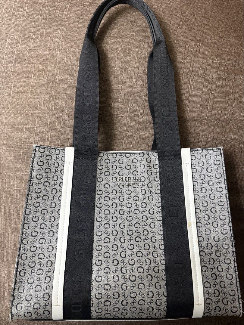Guess Monogram Black White Tote Bag (Category: Tote Bags) located in Cainta. Submitted by amswardrobe (Listing ID 1467837360, Image 1). Description: Guess tote bag in black and white monogram print. Features black branded shoulder straps and white side trim. Metal Guess Los Angeles logo plate on the front. Has a small yellowish stain on the right white strip near the strap, shown in close-up. Roomy everyday bag..