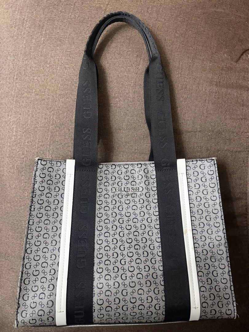 Guess Monogram Black White Tote Bag (Category: Tote Bags) located in Cainta. Submitted by amswardrobe (Listing ID 1467837360, Image 2). Description: Guess tote bag in black and white monogram print. Features black branded shoulder straps and white side trim. Metal Guess Los Angeles logo plate on the front. Has a small yellowish stain on the right white strip near the strap, shown in close-up. Roomy everyday bag..