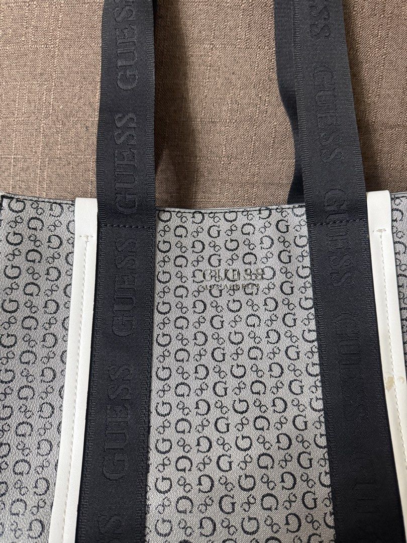 Guess Monogram Black White Tote Bag (Category: Tote Bags) located in Cainta. Submitted by amswardrobe (Listing ID 1467837360, Image 3). Description: Guess tote bag in black and white monogram print. Features black branded shoulder straps and white side trim. Metal Guess Los Angeles logo plate on the front. Has a small yellowish stain on the right white strip near the strap, shown in close-up. Roomy everyday bag..