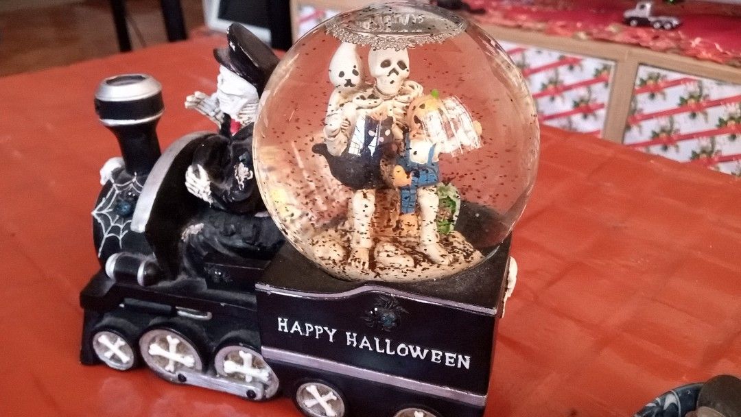 Halloween Skeleton Train Snow Globe Spooky Table Decor (Category: Vintage Collectibles) located in General Trias. Submitted by dwyane09 (Listing ID 1467630026, Image 3). Description: - Spooky Halloween train centerpiece featuring a skeleton conductor - Passenger car includes a snow globe with floating flakes, skeleton figures, and a ghost - Unique bone-patterned wheels and 'HAPPY HALLOWEEN' side text in a sleek black finish -Perfect fun decor for