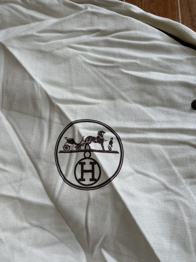 Hermès Canvas Garment Bag Dust Cover (Category: Luxury Accessories) located in Cagayan de Oro. Submitted by aljay02 (Listing ID 1467706491, Image 2). Description: - Color & Material: White heavy cotton weave canvas with brown trim and handles - Branding: Iconic Hermès carriage logo printed near the top right - Closure & Hardware: Full-length front zipper with bronze-tone snap buttons at the top and bottom corners - Ideal Use: Perfect for storing 