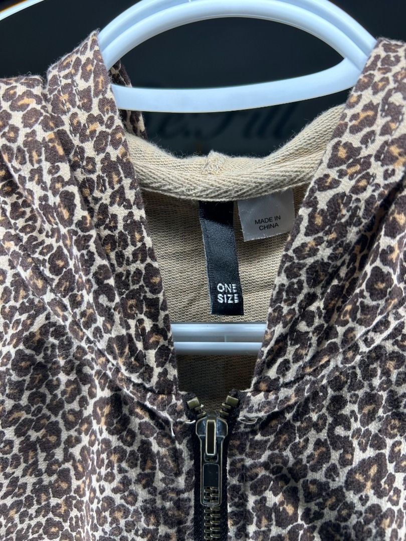H&M Divided Cheetah Print Poncho (Category: Coats, Jackets and Outerwear) located in Taguig. Submitted by re.wear.mnl (Listing ID 1467705413, Image 3). Description: - Style: Leopard print short-sleeve zip-up hoodie - Color: Brown and cream tones - Fit: One size fits most with a relaxed cut - Features: Full metal front zipper and adjustable drawstring hood - Fabric: Lightweight, perfect for layering.