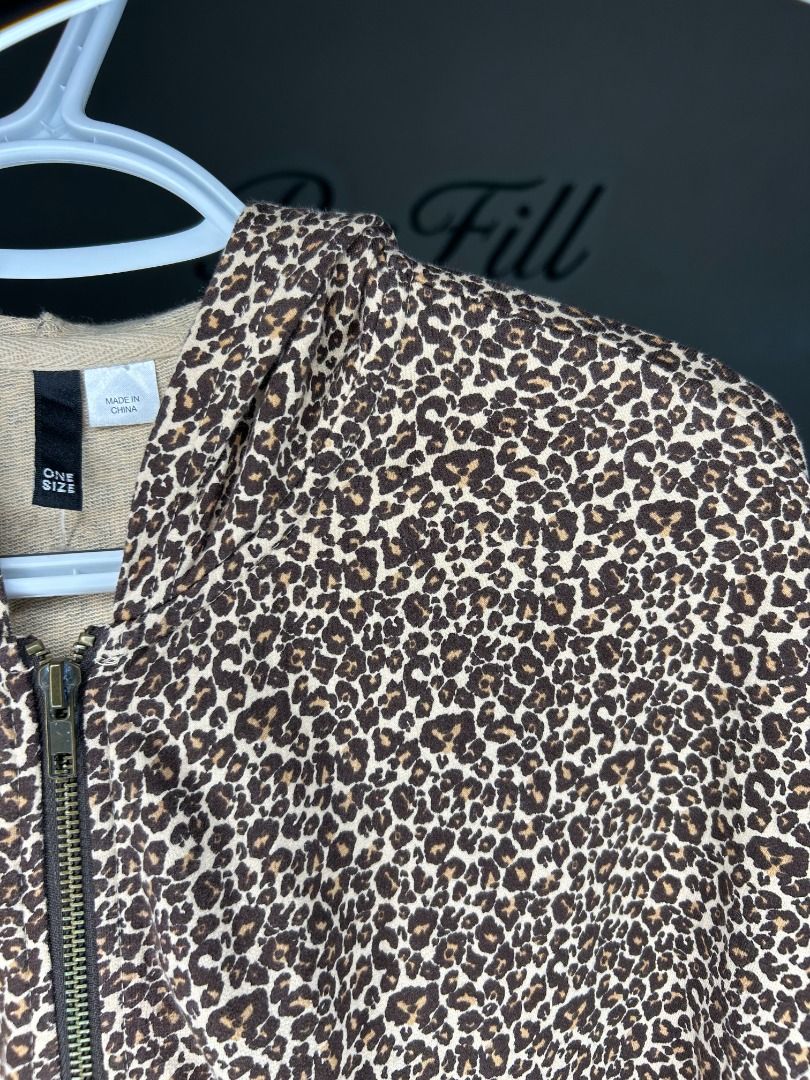 H&M Divided Cheetah Print Poncho (Category: Coats, Jackets and Outerwear) located in Taguig. Submitted by re.wear.mnl (Listing ID 1467705413, Image 2). Description: - Style: Leopard print short-sleeve zip-up hoodie - Color: Brown and cream tones - Fit: One size fits most with a relaxed cut - Features: Full metal front zipper and adjustable drawstring hood - Fabric: Lightweight, perfect for layering.