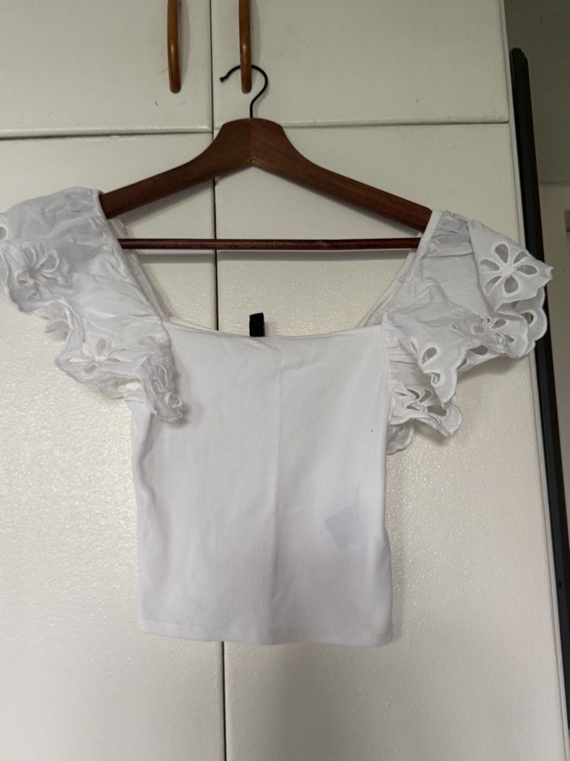H&M Divided White Eyelet Ruffle Sleeve Crop Top (Category: Blouses) located in Iloilo. Submitted by trixiaaa18 (Listing ID 1467623261, Image 1). Description: - Brand: H&M Divided - Size: XS - Color: Clean White - Material: Stretchy ribbed fabric - Design: Square neckline with cut-out flower eyelet ruffles on sleeves - Condition: Excellent, clean.