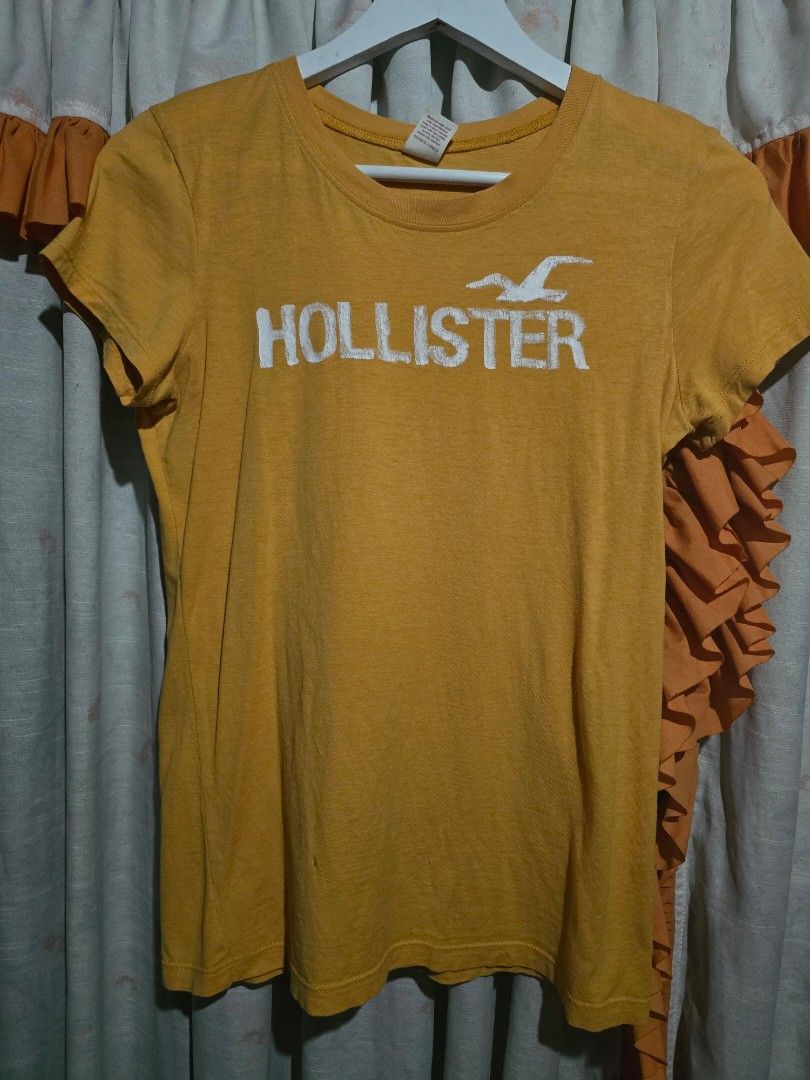 Hollister Mustard Yellow Graphic Tee (Category: Tshirts & Polo Shirts ) located in Dagupan City. Submitted by chislocker14 (Listing ID 1467605965, Image 1). Description: - Brand: Hollister - Size: Large on tag but can only fit s-m - Color: Mustard Yellow - Material: 100% Cotton (Made in Peru) - Style: Classic crew neck, short sleeves - Design: Large white logo graphic on the front - Condition: Soft knit with natural wear and a couple of tiny mino