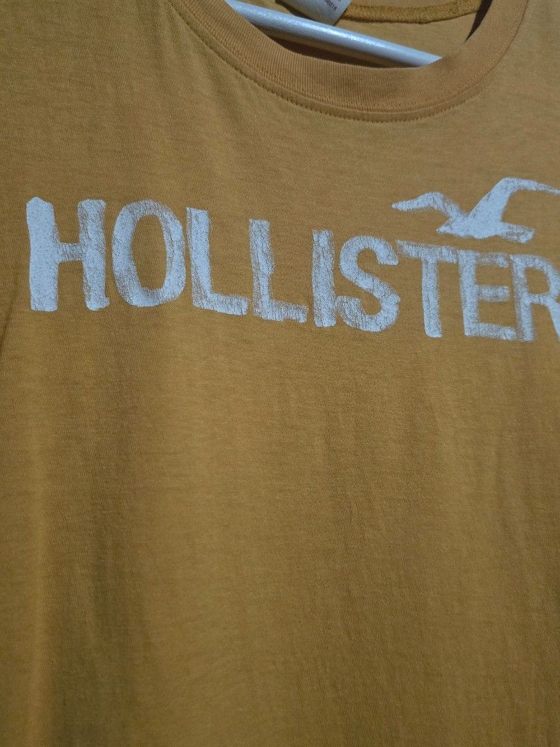 Hollister Mustard Yellow Graphic Tee (Category: Tshirts & Polo Shirts ) located in Dagupan City. Submitted by chislocker14 (Listing ID 1467605965, Image 3). Description: - Brand: Hollister - Size: Large on tag but can only fit s-m - Color: Mustard Yellow - Material: 100% Cotton (Made in Peru) - Style: Classic crew neck, short sleeves - Design: Large white logo graphic on the front - Condition: Soft knit with natural wear and a couple of tiny mino