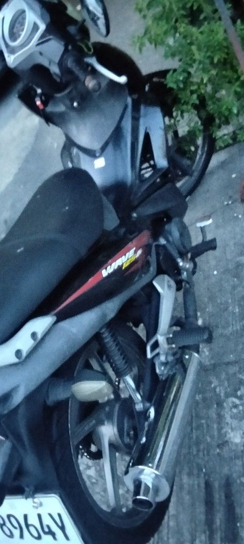 Honda Wave 125R Motorcycle (Category: Motorbikes for Sale) located in Mandaluyong City. Submitted by dhaliwal086 (Listing ID 1467709720, Image 3). Description: Honda Wave 125R motorcycle in black and red. Mileage reads 52631 kilometers. Fuel gauge sits near empty. Chain drive system with stock exhaust pipe. Standard step bars and grab handle attached. License plate reads P8964Y. Engine starts and runs fine. Normal wear from daily commuting..