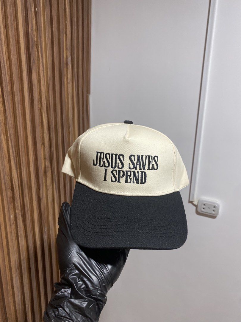 Jesus Saves I Spend Embroidered Cap Cream Black (Category: Caps & Hats) located in Caloocan City. Submitted by heatedcaps4425 (Listing ID 1467802463, Image 1). Description: - Condition: Brand new, never worn (original paper insert still inside) - Design: Cream and black 5-panel structured baseball cap - Embroidery: 'JESUS SAVES I SPEND' text on the front - Fit: Adjustable strap with metal slider in the back - Material: 100% cotton (Made in China)
