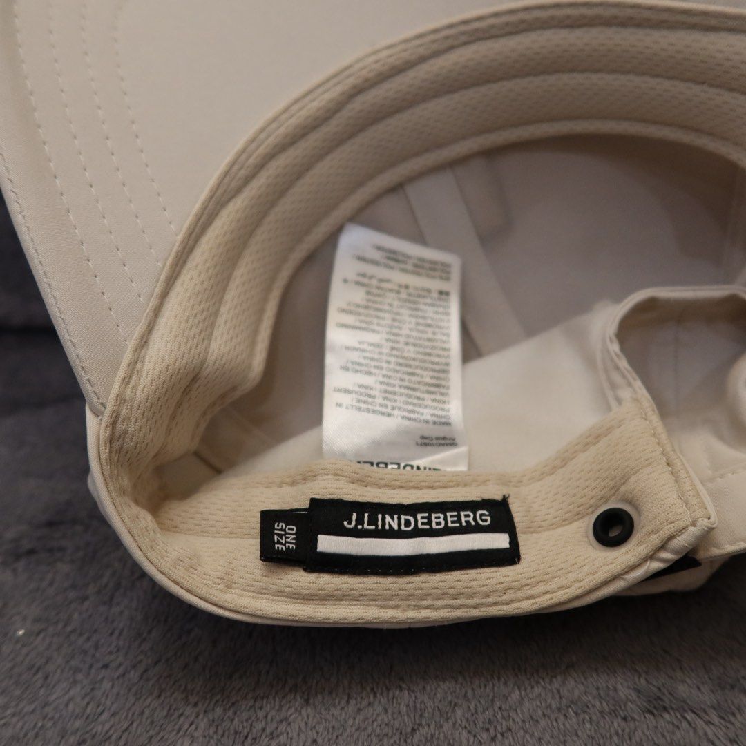j.lindeberg Cap One Size Beige (Category: Caps & Hats) located in Manila. Submitted by gentlewind_62f064 (Listing ID 1467616991, Image 2). Description: - Brand: J.Lindeberg - Color: Neutral beige with black & white embroidered bridge logo - Design: Structured 6-panel with top eyelets and curved brim - Size: One Size (adjustable strap) - Condition: Excellent, clean interior and exterior with no noticeable flaws - Origin: Made in China.